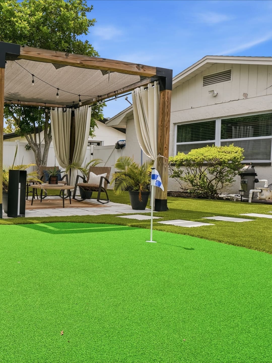 A rack of putters and colored balls at the near end of the green, the cabana lit beyond.